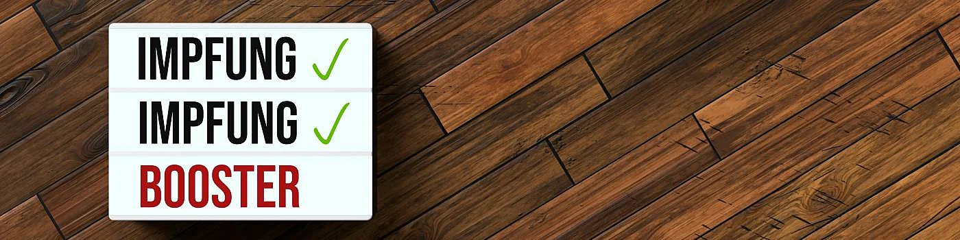 Headerbild, Hintergrund braunes Holz, Schild mit Schrift: Impfen, Impfen, Booster