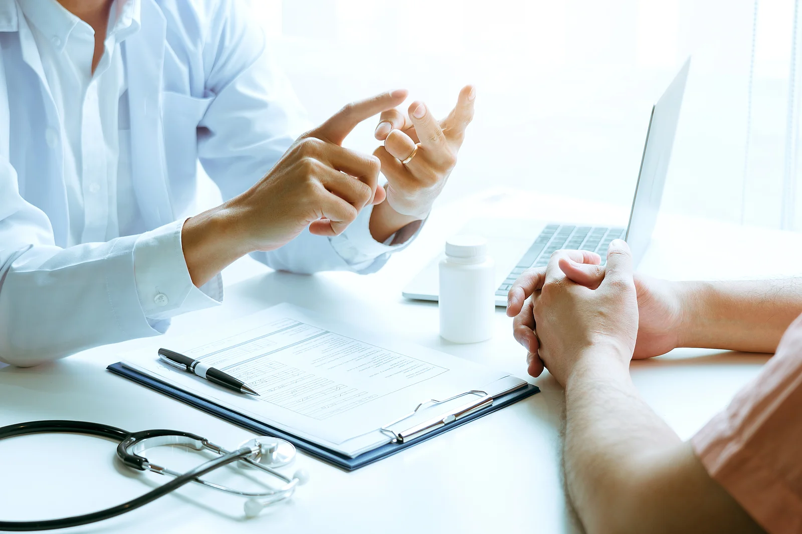 Male patient listening to doctor at desk and consulting with hea Male patient listening to doctor at desk and consulting with hea