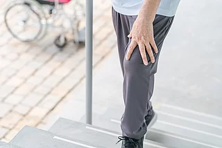 Person geht langsam eine Treppe hinauf und stützt sich dabei ab. 